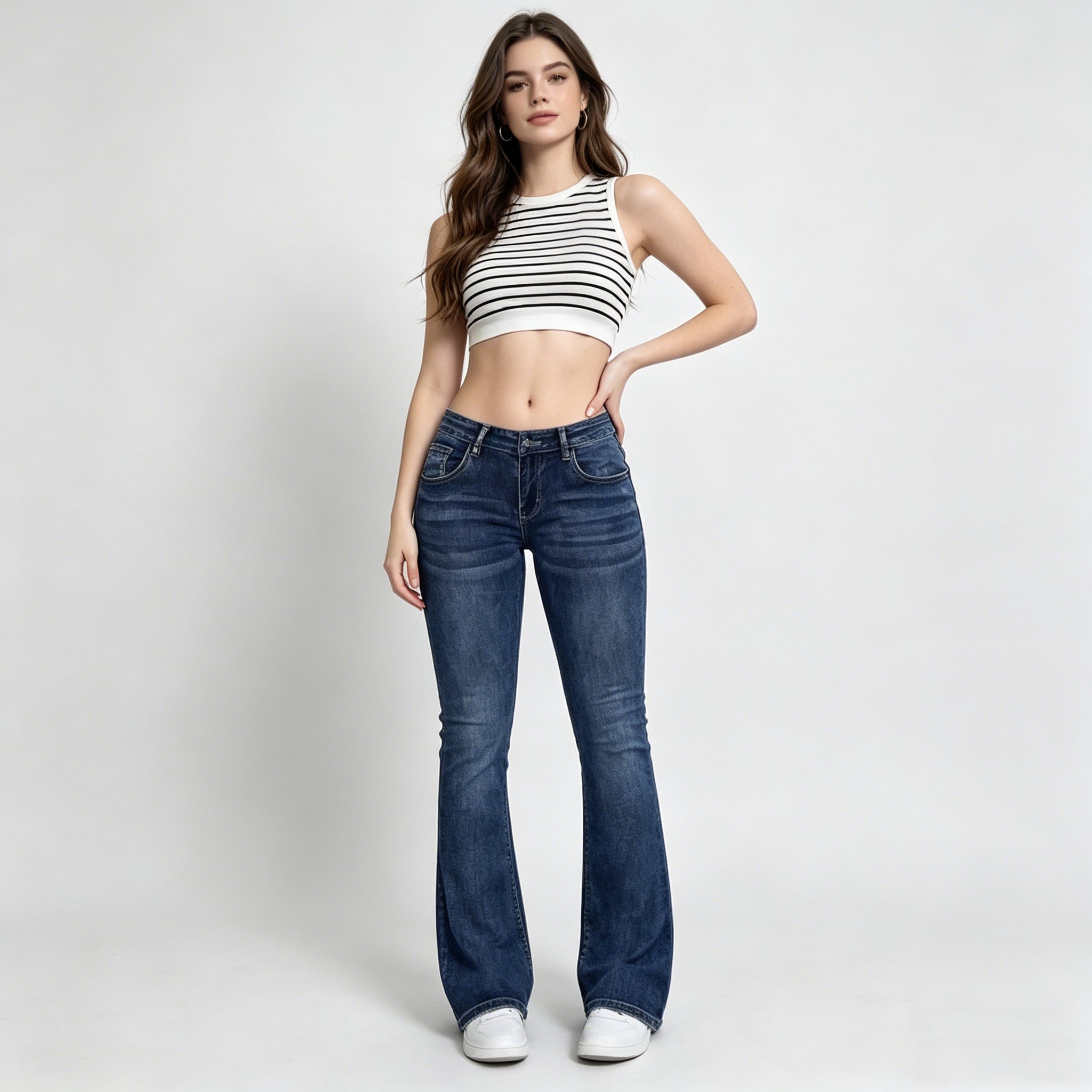 Woman wearing a striped crop top and blue jeans on a white background
