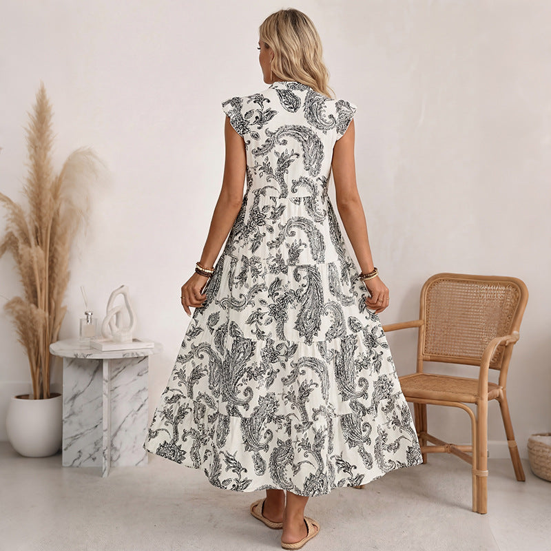 Woman wearing a white dress with black floral pattern in a minimalistic room.