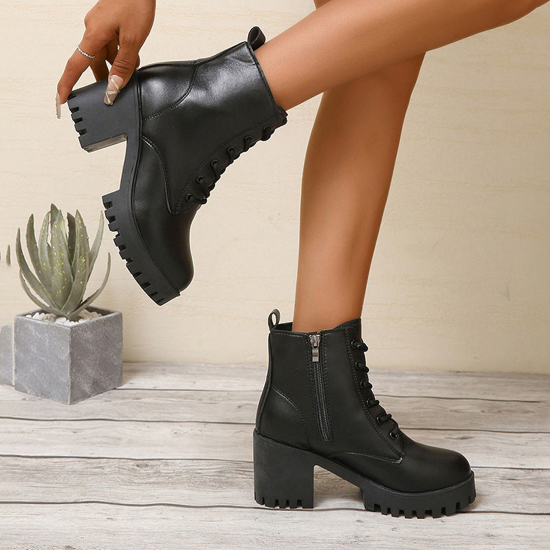 Person wearing black leather boots with a neutral background