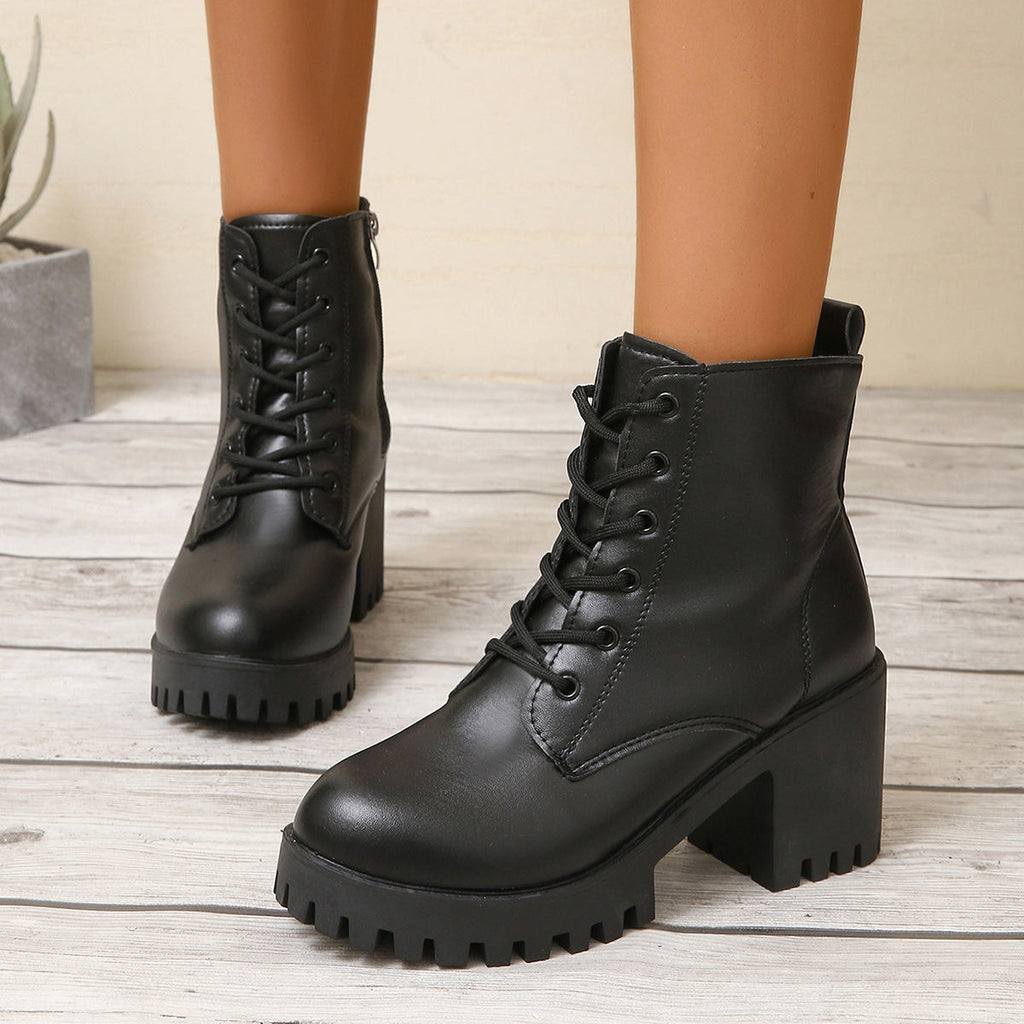 Black leather boots with chunky sole on a wooden floor