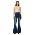 Woman wearing a beige bodysuit and blue flared jeans on a white background