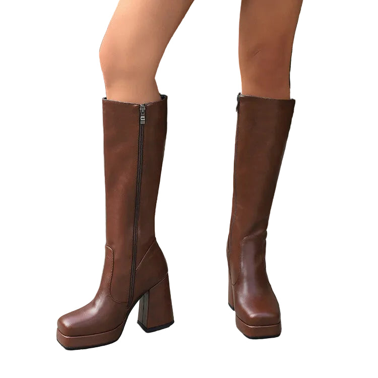 Brown knee-high boots with a platform sole worn by a person standing on a pavement.