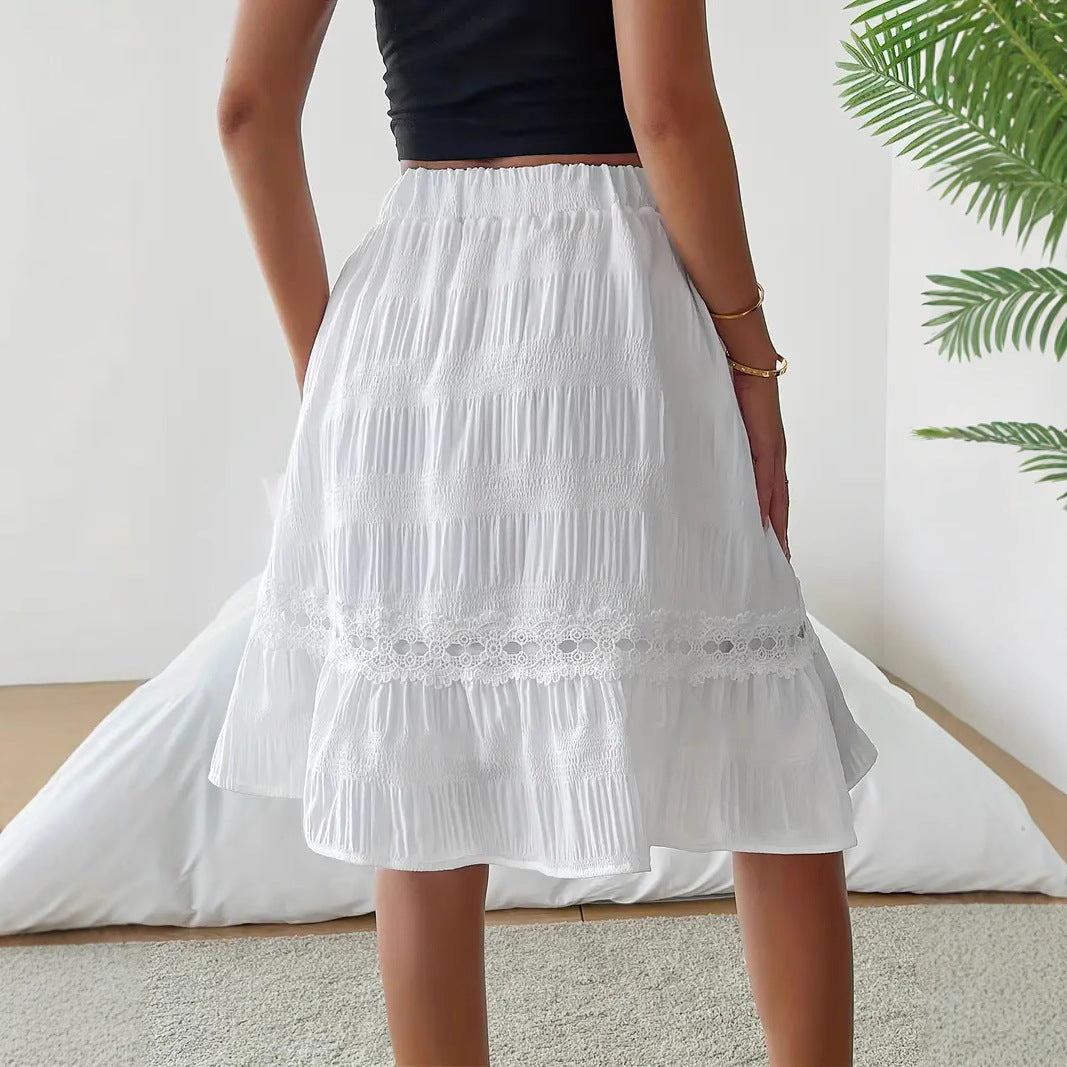 Person wearing a white skirt with lace details in a minimal indoor setting.