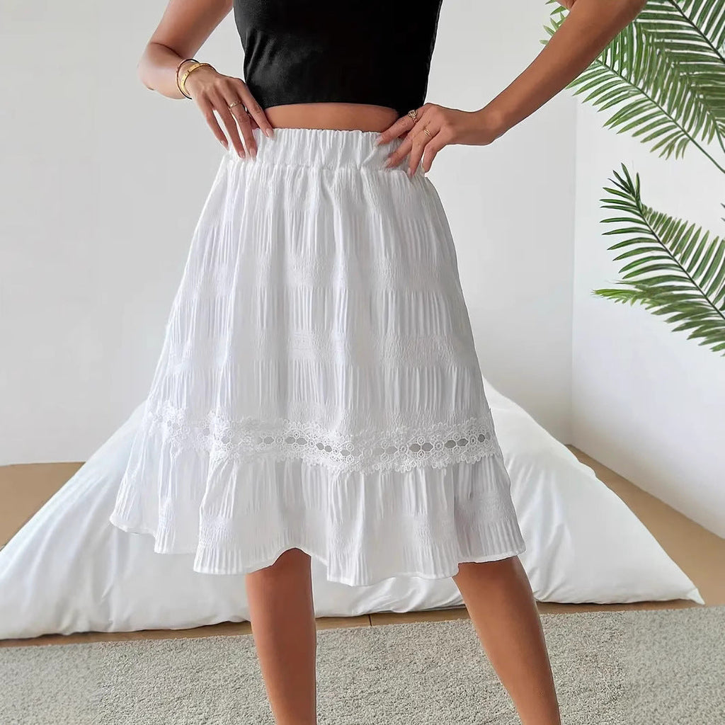 Person wearing a white skirt with lace trim in a minimal indoor setting.