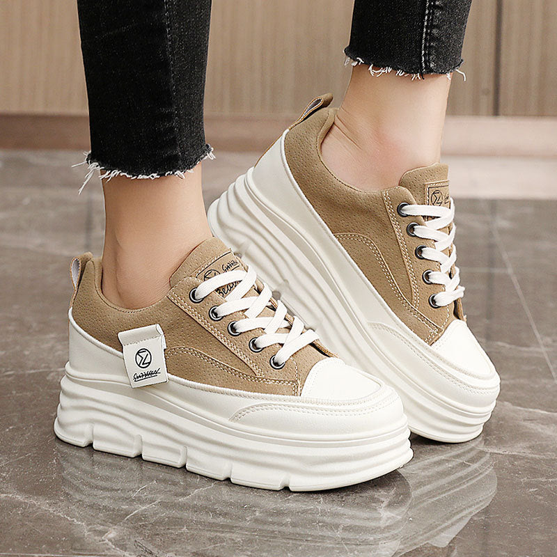 Brown sneakers with white soles worn by a person on a tiled floor.