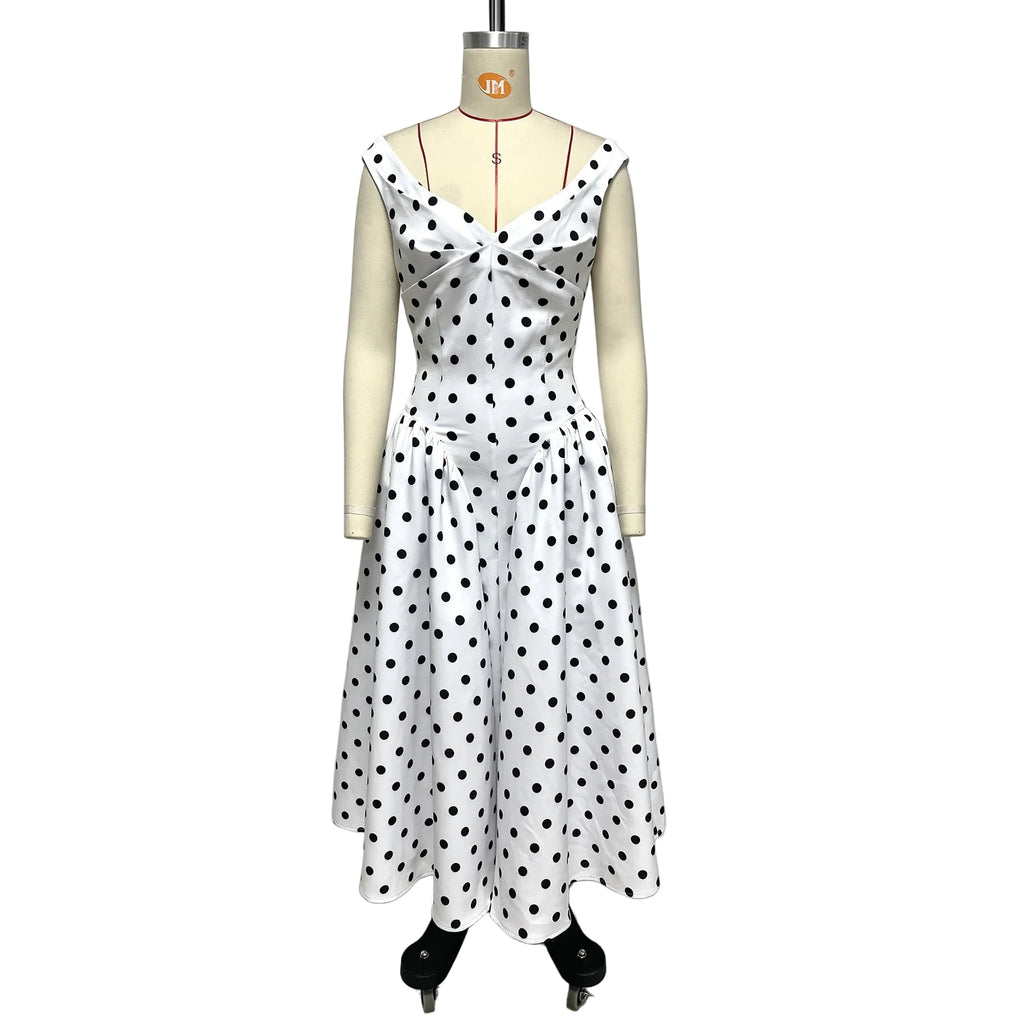 White dress with black polka dots on a mannequin against a plain background
