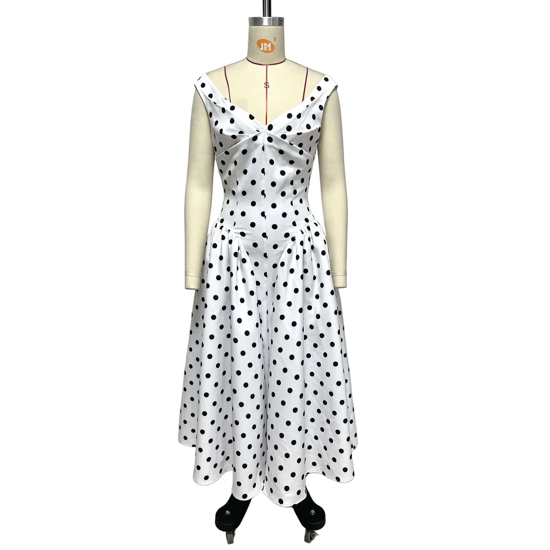 White dress with black polka dots on a mannequin against a plain background